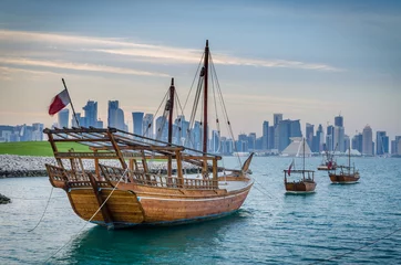 Fotobehang Dhows moored off Museum Park in central Doha, Qatar, Arabia, with some of the buildings from the city's commercial port in the background. © matpit73