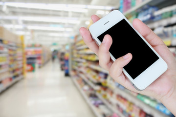 hand hold smartphone with supermarket background