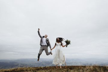 beautiful fabulous happy  bride and stylish groom jumping  on th