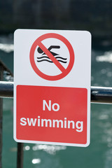 No Swimming sign on railings besides harbour