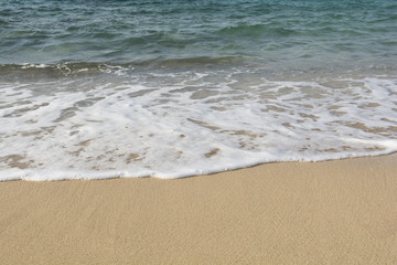 Fototapeta na wymiar Close up of foamy soft wave on sand beach