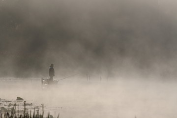 Fisherman in boat in foggy morning