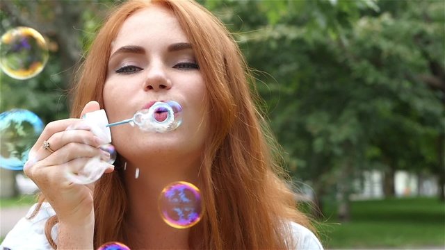 Romantic young, beautiful girl inflating colorful soap bubbles. close up