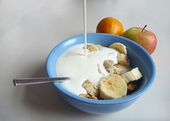 A  bowl with granola and bananaand poured milk
