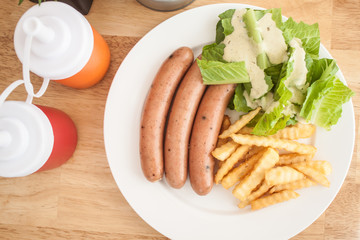 Three pieces of sausage with fresh vegetables, fried potatoes se