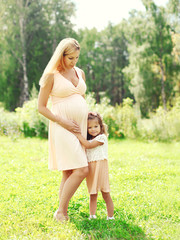 Fototapeta na wymiar Happy pregnant woman, little child daughter hugging mother in su