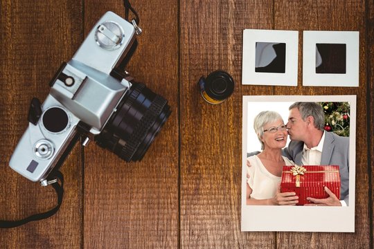 Photo of mature couple holding gift on wooden table
