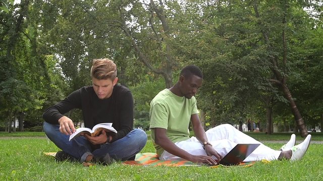 Young students reading books at the school park. slow motion