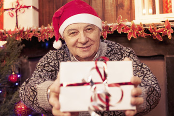 mature man holding a red christmas gift box in his hands