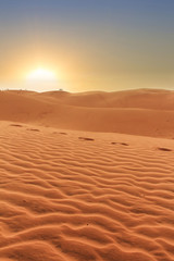 Fototapeta na wymiar sunset in desert landscpe, footprints in rippled sand