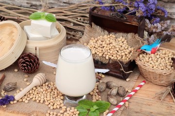 Soy milk and soybeans on wood background.