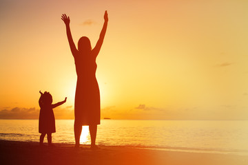 silhouette of happy mother and little daughter at sunset