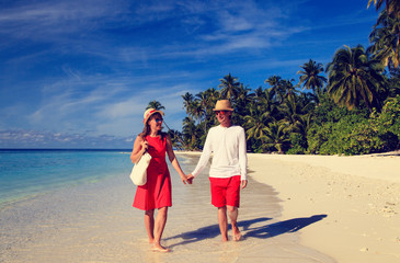 happy loving couple walking on tropical beach