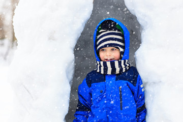 Little boy having fun in winter snow cave