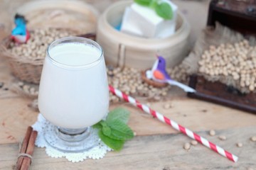 Soy milk and soybeans on wood background.