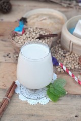 Soy milk and soybeans on wood background.
