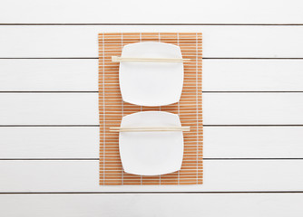 Empty plates and chopsticks on white wooden background. Top view with copy space