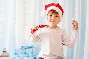 Smiling funny child in Santa red hat holding Christmas gift in h