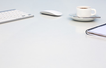 Bright Open Space Office White Table Angle View with Coffee Mug Opened Blank Notepad and Computer Keyboard and Mouse on Desk Side View with Reflections and Copy Space