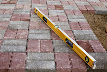 paving slabs and tools for measuring the level. Paving works of paving tiles. A new gray-red...