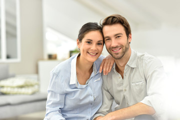 Portrait of cheerful couple sitting in sofa at home