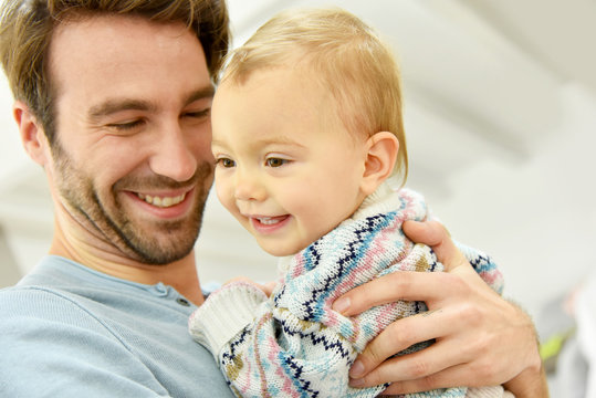 Portrait Of Young Man Holding Baby In Arms