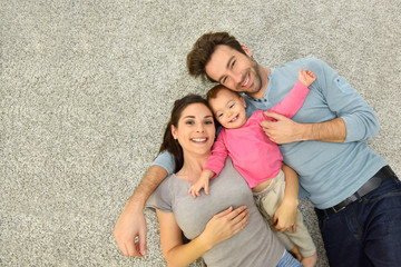 Upper view of family of three laying on carpet