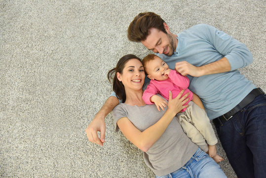 Upper view of family of three laying on carpet