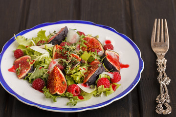 Salad with figs and raspberries, dressed with raspberry sauce and Parmesan cheese