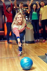 Fototapeta na wymiar happy young woman throwing ball in bowling club