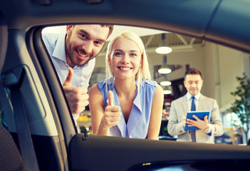 happy couple with car dealer in auto show or salon