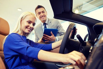 happy woman with car dealer in auto show or salon