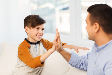 happy father and son doing high five at home