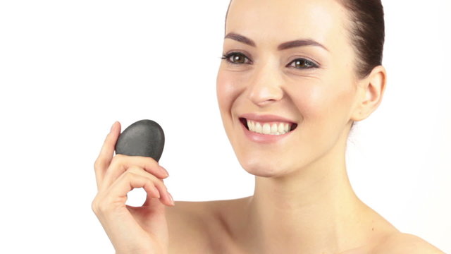 Young woman in a beauty style pose holding a spa rock and laughing