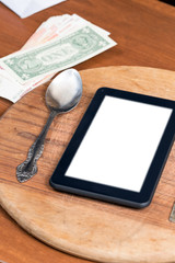 Black tablet pc on wooden table with fork and knife