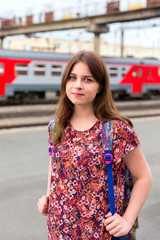 Young girl smiling on train station platform with bags