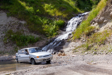 Fototapeta premium The car under a waterfall