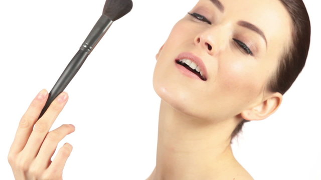 Beautiful young woman using a large make up brush to apply powder