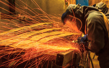 worker in automotive industry movement work grinding parts with sparks