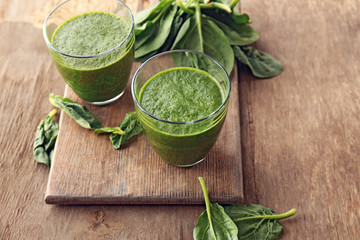 Glasses of spinach juice on wooden background