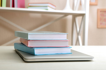 Stack of books with laptop on table close up