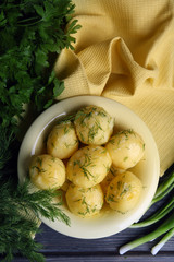 Boiled potatoes with greens in bowl on table close up