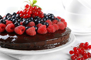 Delicious chocolate cake with summer berries on wooden table, closeup
