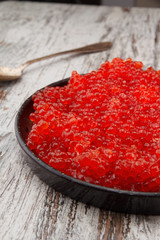 Red caviar in a black plate over a vintage background
