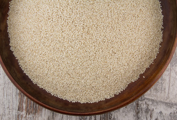 Sesame seeds in a wooden plate over wooden background