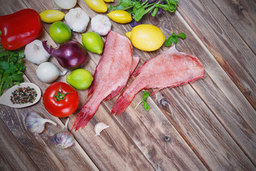 two raw fishes of bass with lime,.by tomatoes, pepper, onion, lemon, basil,.by a garlic, parsley and spices