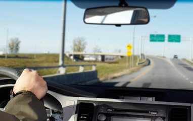 Hand of man driving on a highway.