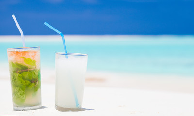 exotic mojito and pina colada cocktails on white sand beach