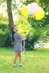 Happy little girl in striped dress with colourful balloons in the park