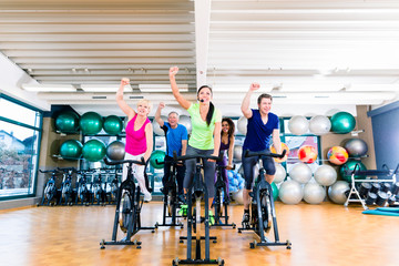 Group of men and women spinning on fitness bikes in gym